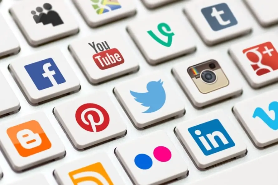 Un gros plan sur les touches d'un clavier d'ordinateur, chacune ornée d'un logo de réseau social comme Facebook, YouTube et Instagram, symbolisant la présence en ligne d'une entreprise.