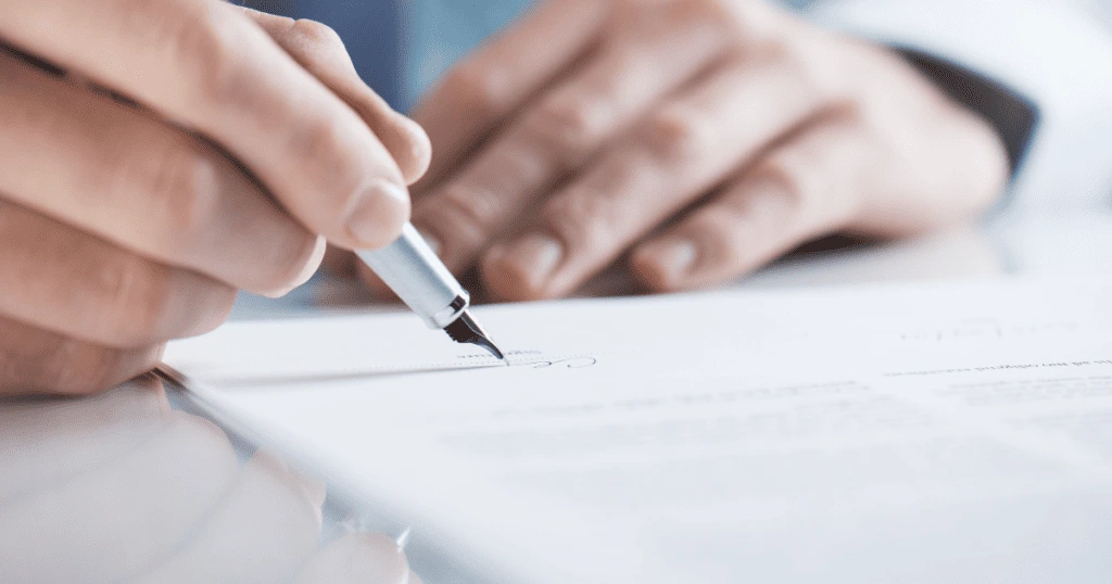 Une personne en train de signer un document, symbolisant la validation et la finalisation d'un contrat ou d'une facture.