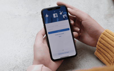Deux mains tenant un smartphone qui affiche la page de connexion à l'application Facebook, symbolisant la gestion des avis clients et de la réputation en ligne sur la plateforme.
