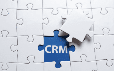 Un puzzle blanc avec un trou au centre, révélant un fond bleu avec le sigle "CRM" et une pièce de puzzle blanche en train d'être insérée, symbolisant le CRM comme la solution essentielle (la pièce manquante) pour l'entreprise.