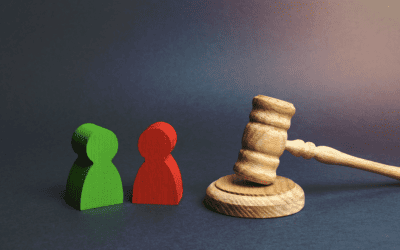 Deux silhouettes de figurines (une verte, une rouge) face à un marteau de juge (maillet), symbolisant un litige entre deux parties et le recours à la médiation ou à la justice suite à un désaccord sur un devis.