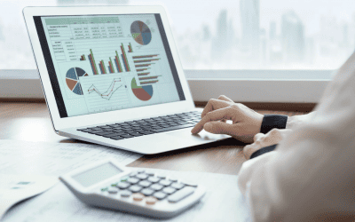 Une personne travaillant sur un ordinateur portable qui affiche des graphiques financiers et un tableau de données, avec une calculatrice à côté. L'image symbolise l'analyse financière et la gestion des notes de frais.