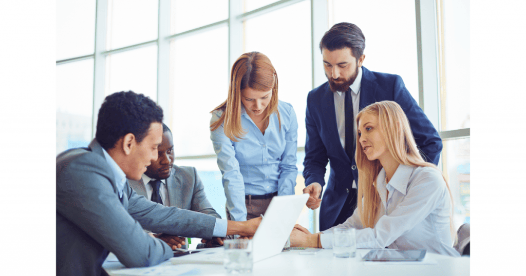 Une équipe de professionnels en pleine discussion autour d'un ordinateur portable, symbolisant le travail collaboratif pour améliorer la relation client et les stratégies d'entreprise. - Digitandco.