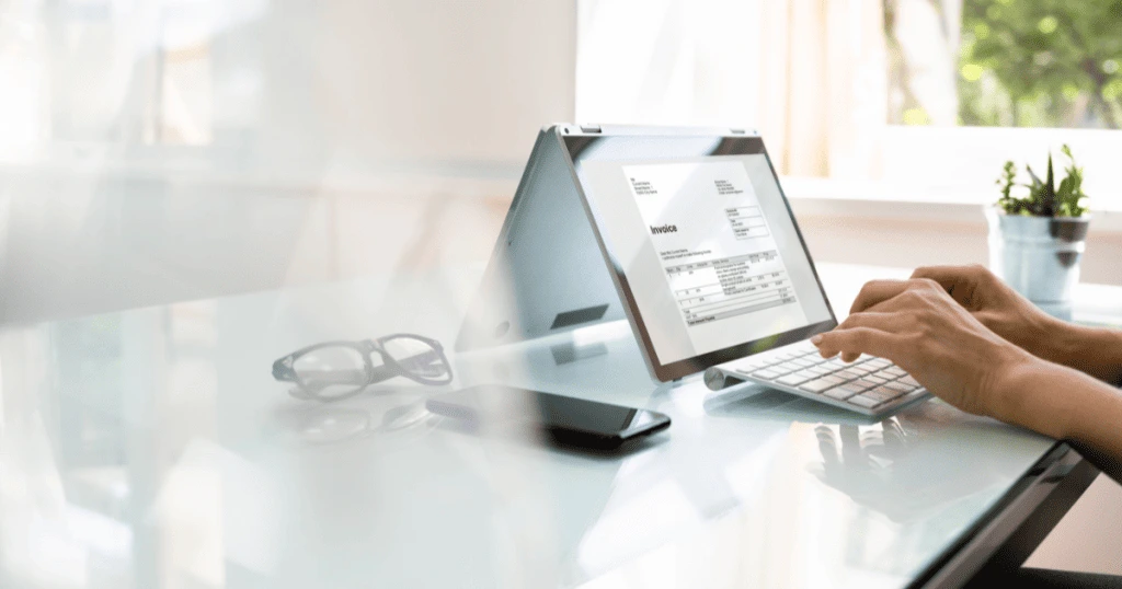 Une personne tapant sur un ordinateur portable affichant une facture électronique, symbolisant la facilité et l'efficacité de la facturation numérique par rapport à la méthode papier - Digitandco.