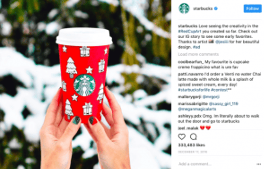 Une capture d'écran d'un post Instagram de Starbucks montrant deux mains tenant une tasse de café rouge décorée pour Noël. L'image est un exemple de contenu généré par l'utilisateur (UGC), mettant en évidence l'importance de cette tendance digitale en 2022. - Digitandco.