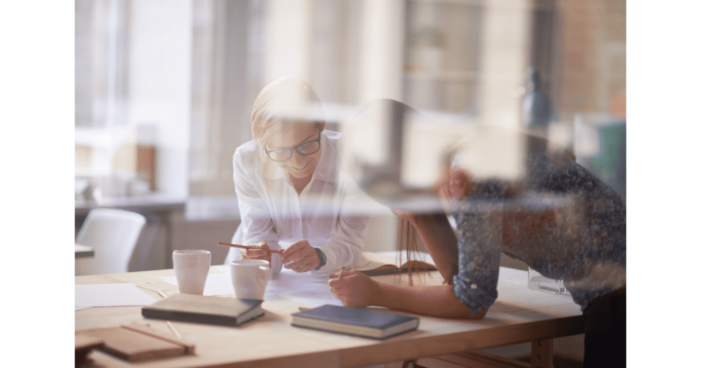 Deux collègues discutant et collaborant autour d’une table, symbolisant le community management et l’échange